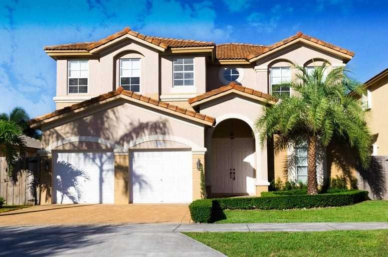 2-story Mediterranean style single-family home with two-car garage and palm trees.